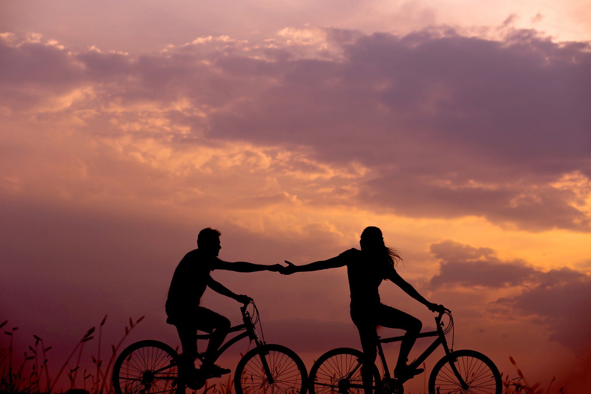 Couple cycling and holding hands